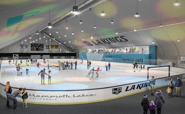 People skating under string lights at an outdoor ice rink