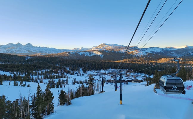 Red cable car gondola over a snowy alpine valley